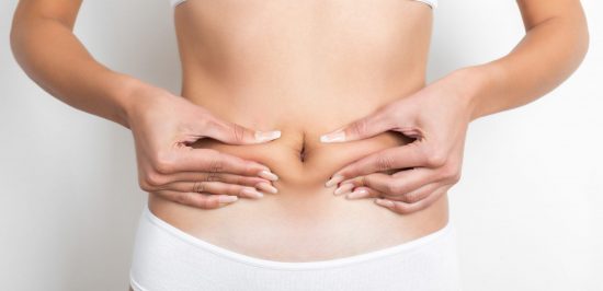Woman pinching her stomach on white background